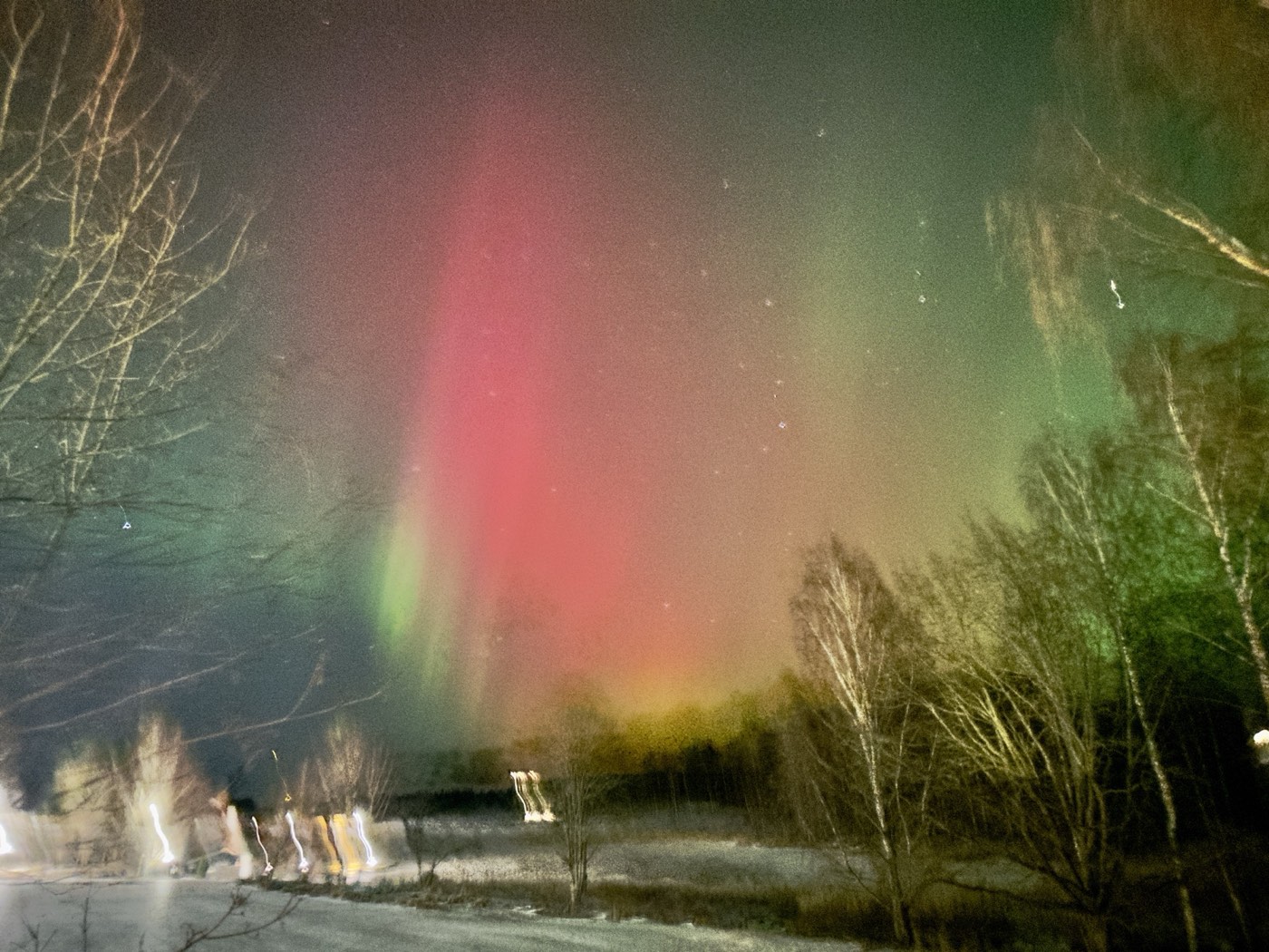 Red green aurora borealis pillars blazing over frozen Finnish lake Rovaniemi